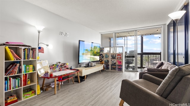 living room with a textured ceiling, light hardwood / wood-style flooring, and a wall of windows