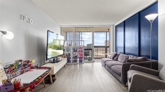 living room with wood-type flooring, a textured ceiling, and a wall of windows