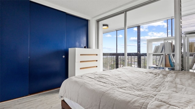 bedroom featuring hardwood / wood-style flooring, a textured ceiling, and a wall of windows