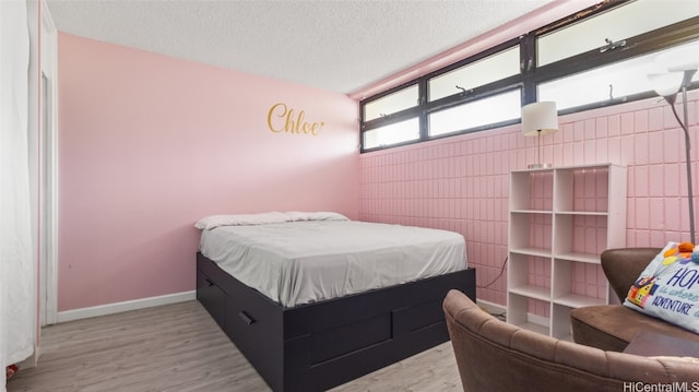 bedroom featuring a textured ceiling and light hardwood / wood-style flooring