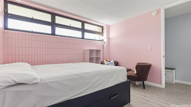 bedroom with a textured ceiling and light wood-type flooring