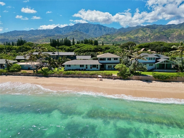 drone / aerial view with a water and mountain view and a view of the beach