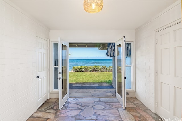 doorway to outside featuring french doors, brick wall, and a water view