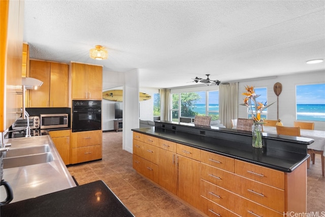 kitchen featuring a kitchen island, a textured ceiling, black oven, and ceiling fan