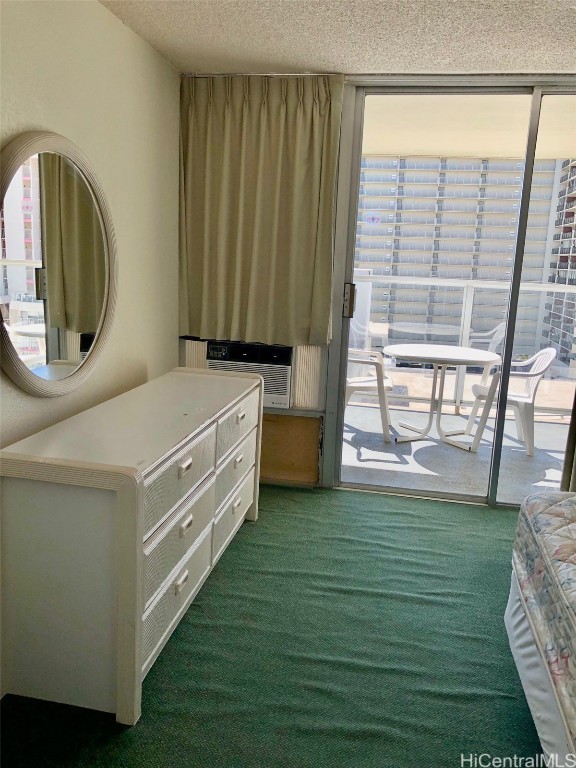 bedroom featuring cooling unit, a textured ceiling, and dark colored carpet