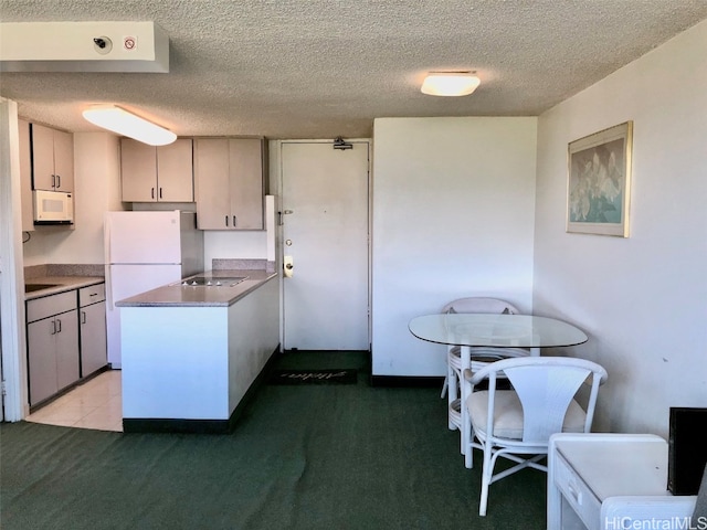 kitchen featuring white appliances, a textured ceiling, and light colored carpet