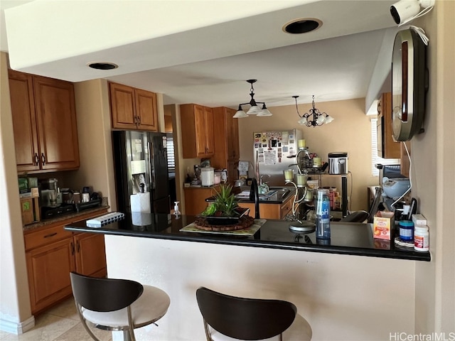 kitchen featuring a breakfast bar area, kitchen peninsula, refrigerator, decorative light fixtures, and stainless steel refrigerator