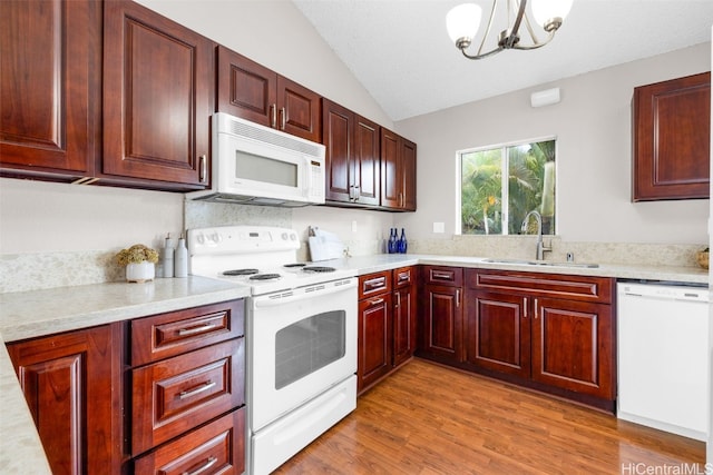 kitchen with lofted ceiling, sink, decorative light fixtures, light hardwood / wood-style flooring, and white appliances