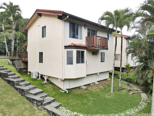 view of side of property featuring a balcony, a yard, and ac unit