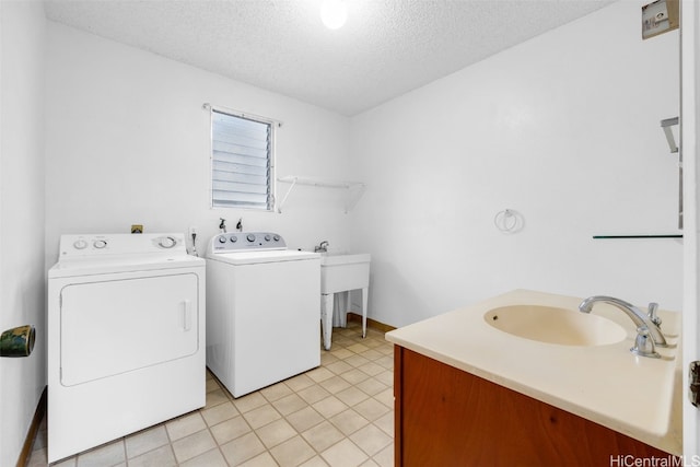 clothes washing area with sink, light tile patterned floors, a textured ceiling, and independent washer and dryer