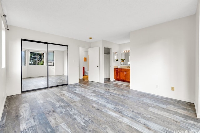 unfurnished bedroom with light hardwood / wood-style floors, a closet, and ensuite bathroom