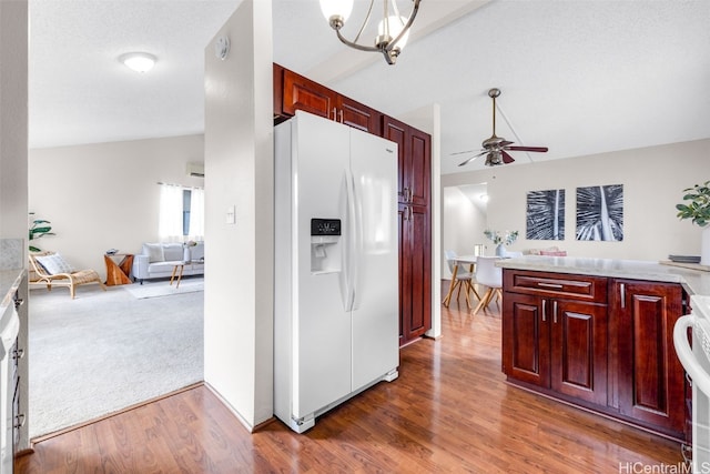 kitchen featuring lofted ceiling, ceiling fan with notable chandelier, dark wood-type flooring, and white fridge with ice dispenser