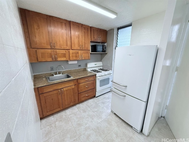 kitchen with a textured ceiling, sink, light stone counters, and white appliances