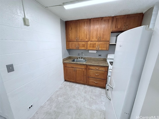 kitchen with sink, white fridge, and a textured ceiling