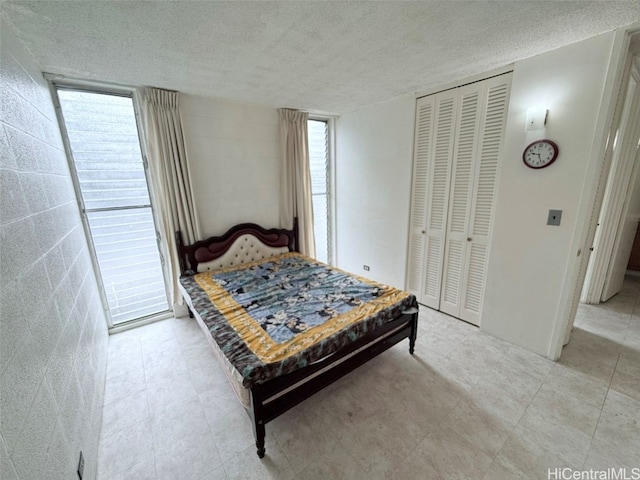 bedroom with multiple windows, a textured ceiling, and a closet