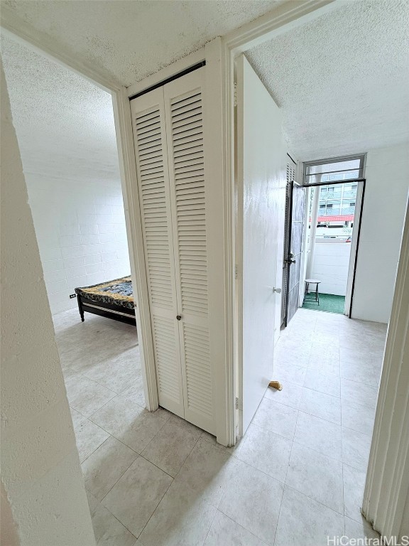 hallway featuring a textured ceiling and light tile patterned floors