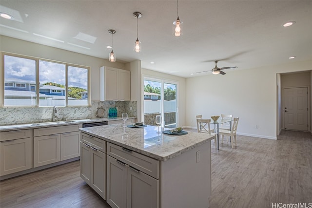 kitchen featuring sink, a center island, light hardwood / wood-style flooring, and pendant lighting