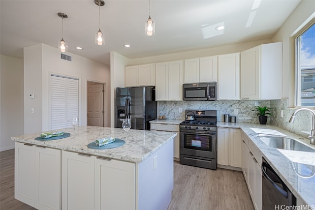 kitchen with white cabinets, a healthy amount of sunlight, hanging light fixtures, sink, and stainless steel appliances