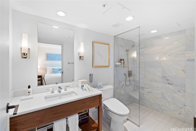 bathroom featuring toilet, vanity, and tiled shower