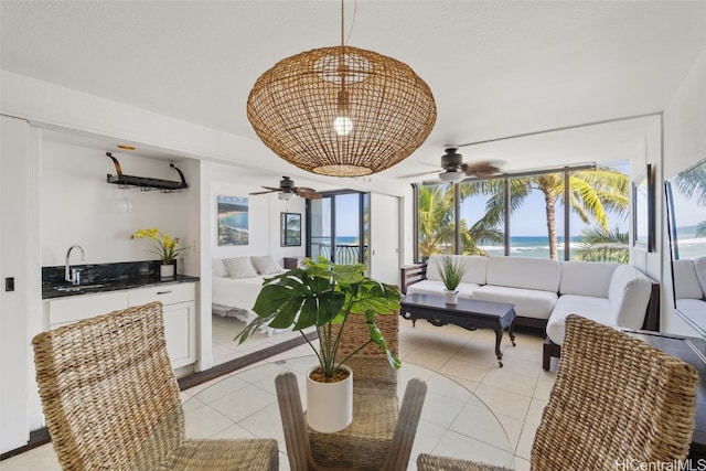 tiled dining area with ceiling fan, sink, and a water view