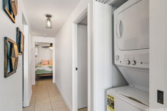 clothes washing area with ceiling fan, light tile patterned floors, and stacked washer and clothes dryer