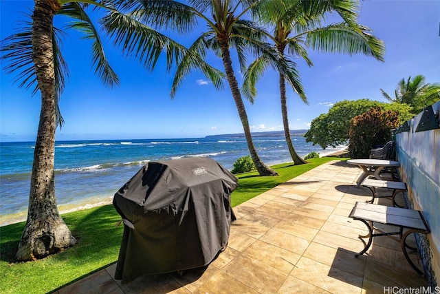 view of patio / terrace with area for grilling, a water view, and a view of the beach