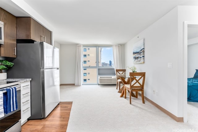 kitchen featuring stainless steel fridge, range with electric stovetop, a wall unit AC, and light colored carpet