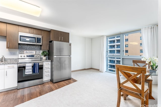 kitchen with decorative backsplash, stainless steel appliances, and light hardwood / wood-style floors