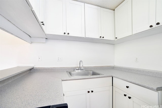 kitchen featuring sink, white cabinets, and a textured ceiling