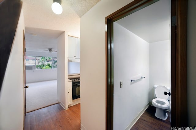 bathroom with a textured ceiling, hardwood / wood-style flooring, toilet, and ceiling fan