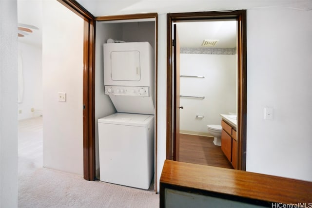 laundry room with stacked washer and dryer and light colored carpet