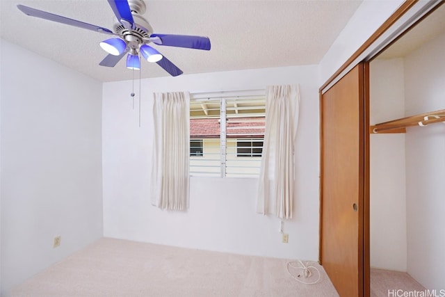 unfurnished bedroom featuring a closet, ceiling fan, carpet flooring, and a textured ceiling