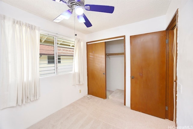 unfurnished bedroom with a closet, a textured ceiling, light colored carpet, and ceiling fan