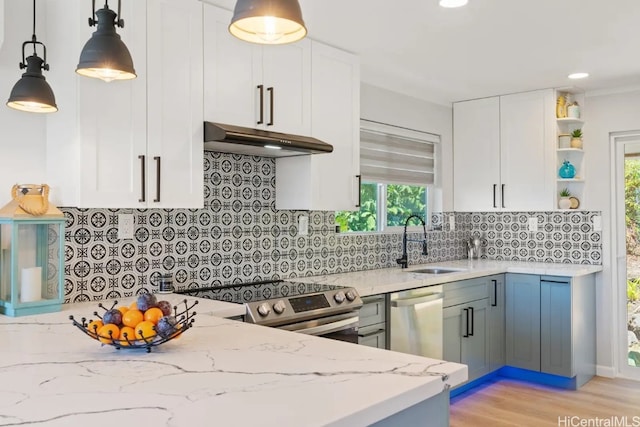 kitchen with stainless steel appliances, sink, light stone countertops, decorative light fixtures, and white cabinets