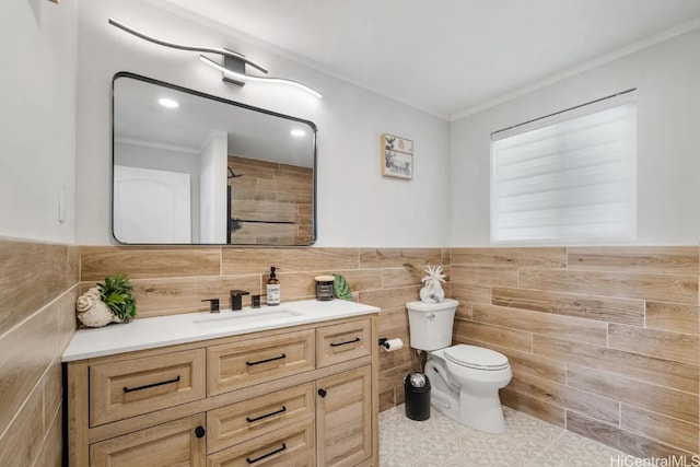 bathroom featuring tile walls, toilet, vanity, crown molding, and tile patterned flooring