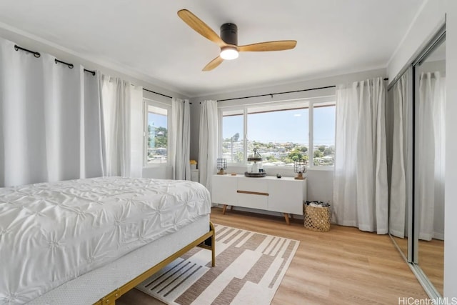 bedroom with a closet, light hardwood / wood-style floors, and ceiling fan