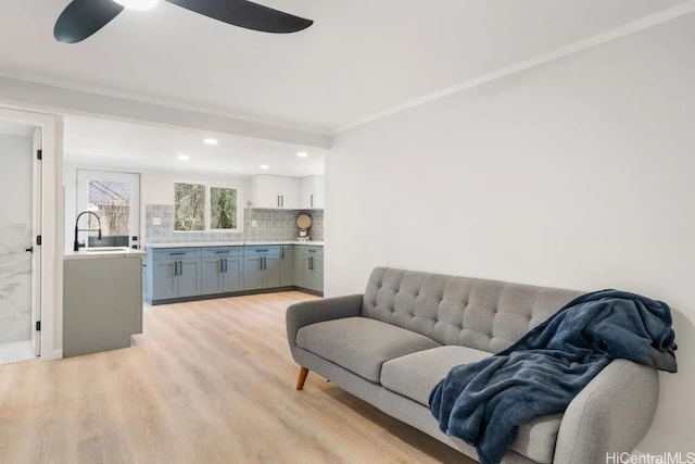 living room with light hardwood / wood-style floors, sink, and ceiling fan