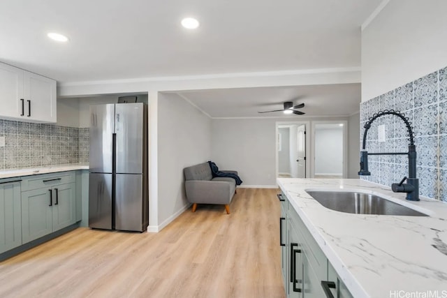 kitchen with sink, light wood-type flooring, backsplash, stainless steel fridge, and ceiling fan