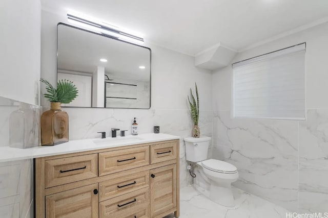 bathroom with vanity, toilet, and tile walls