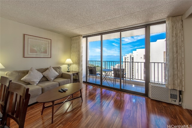 living room with floor to ceiling windows, a textured ceiling, a water view, and hardwood / wood-style flooring