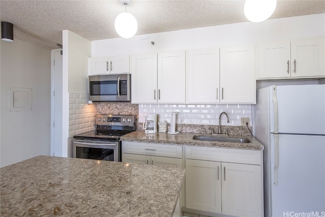 kitchen with white cabinets, backsplash, sink, decorative light fixtures, and stainless steel appliances