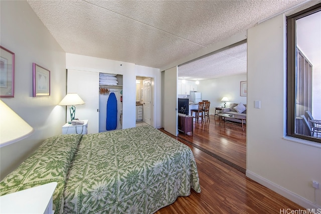 bedroom featuring hardwood / wood-style floors, white fridge, a textured ceiling, and a closet