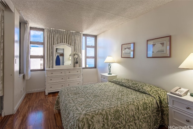 bedroom with a textured ceiling and dark hardwood / wood-style flooring