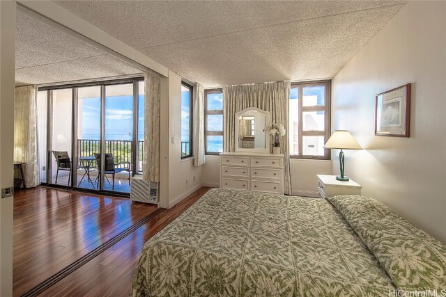 bedroom featuring dark wood-type flooring, access to outside, a textured ceiling, and floor to ceiling windows