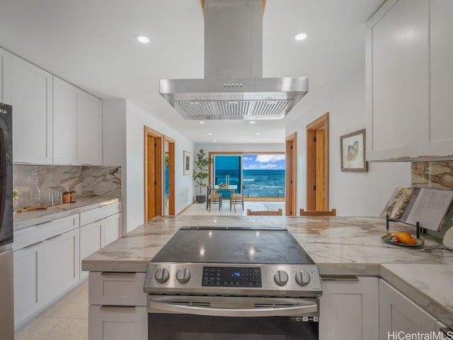 kitchen with light stone countertops, island exhaust hood, appliances with stainless steel finishes, and white cabinetry