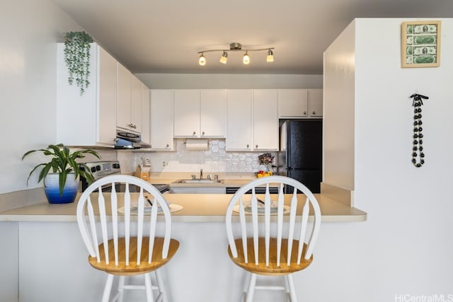 kitchen with white cabinetry, a kitchen breakfast bar, stainless steel range with electric cooktop, and black refrigerator