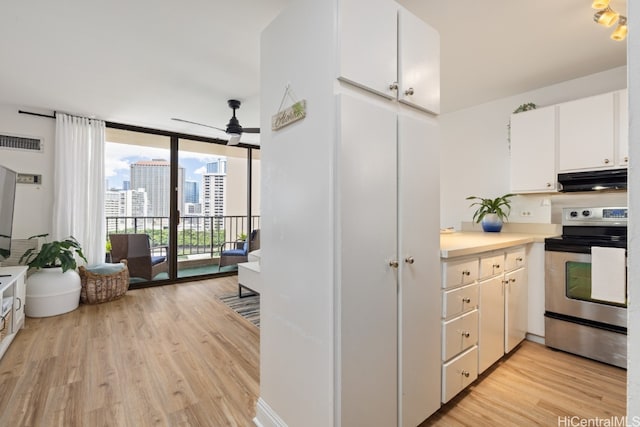 kitchen featuring stainless steel electric range, ceiling fan, light wood-type flooring, white cabinets, and floor to ceiling windows