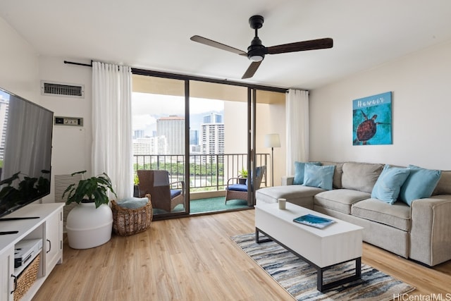 living room with a wall of windows, light wood-type flooring, and ceiling fan