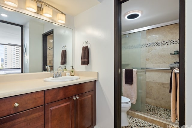 bathroom featuring a shower with door, vanity, toilet, and tile patterned flooring