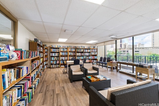 living area with a drop ceiling and hardwood / wood-style floors